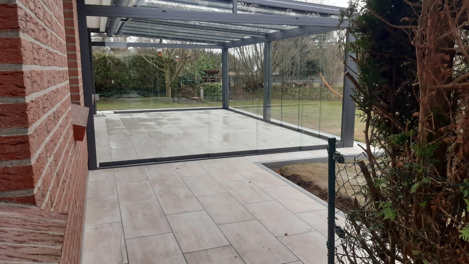 Glasschiebewand als Windschutz zur Gartenseite