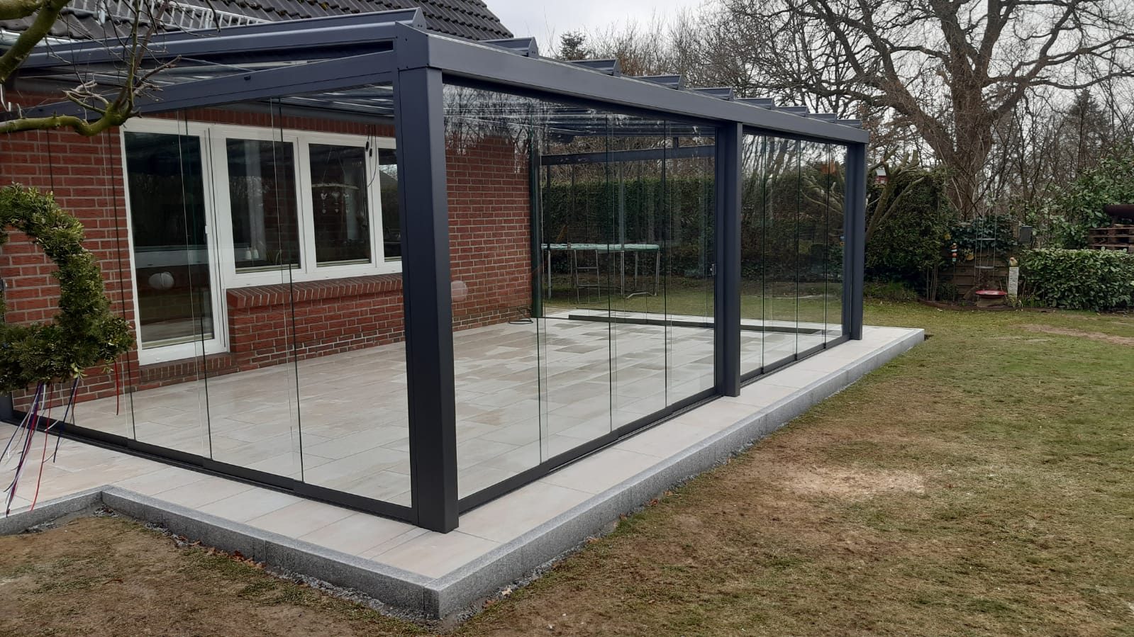 Glasschiebewand rund um eine überdachte Terrasse
