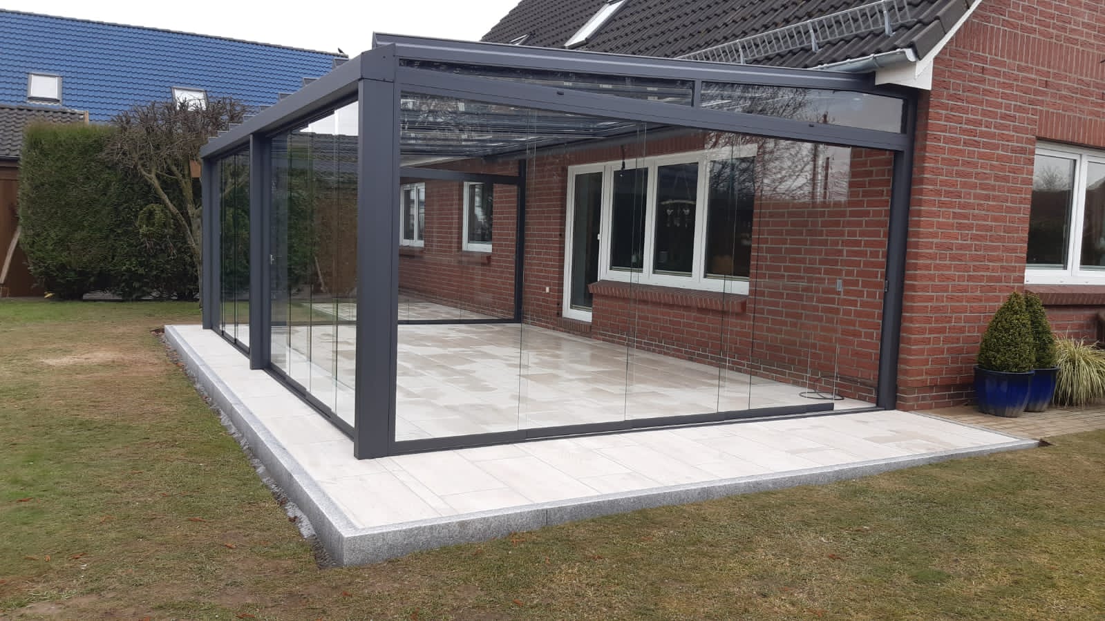Kaltwintergarten mit Glasschiebewänden und verlegtem Fliesenboden, komplett von Hiller Terrassendächer gebaut