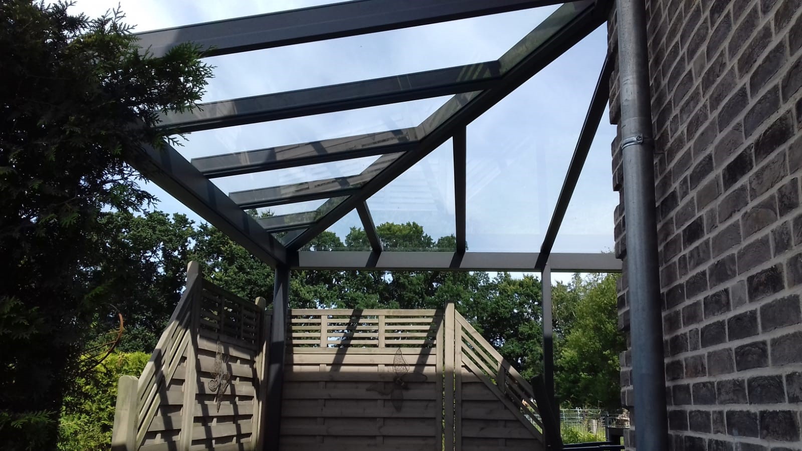 Blick von unten auf die Aluminiumkonstruktion eines Terrassendachs mit Glaseindeckung