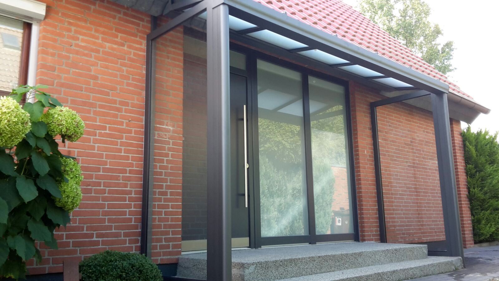 Modernes Glasvordach an einem Klinkerhaus